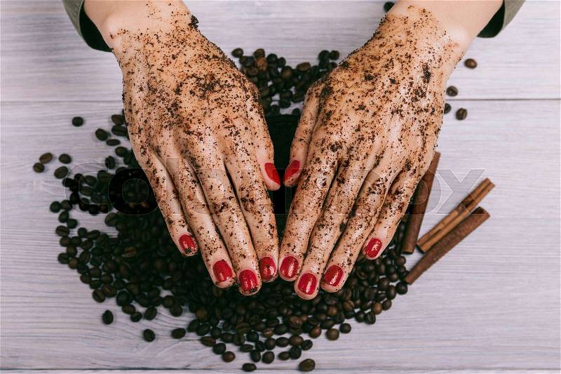 Female hands with red manicure and coated coffee scrub close-up, top view, stock photo