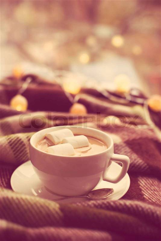 Cozy winter home, cup of coffee with marshmallows, warm blanket and Christmas lights, stock photo