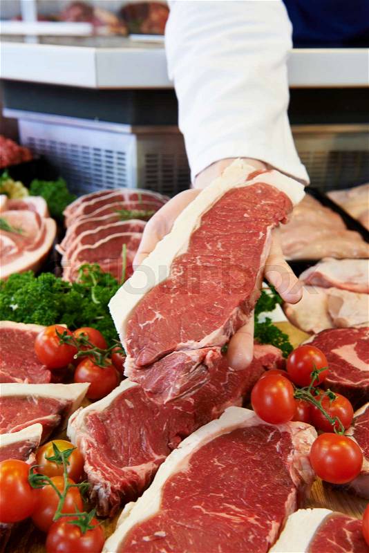 Butcher Showing Customer Sirloin Steak In Refrigerated Display, stock photo