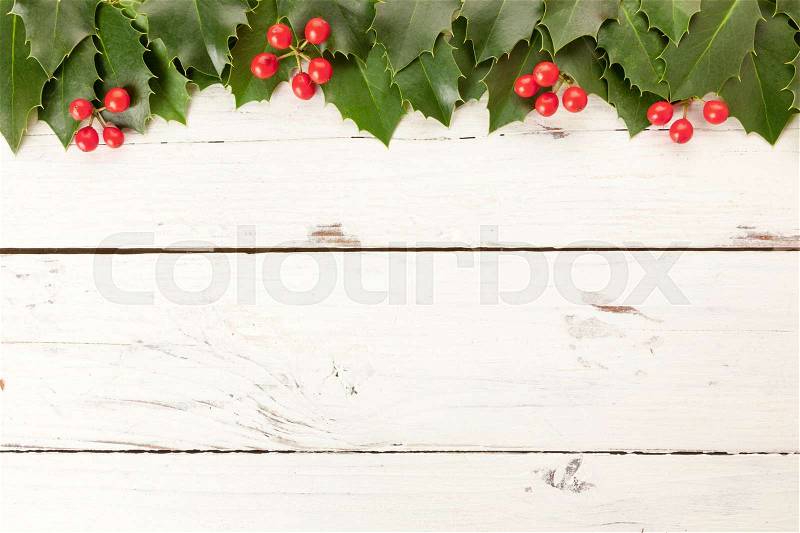 Holly leaves with berries on rustic white wooden background, large copy space, stock photo