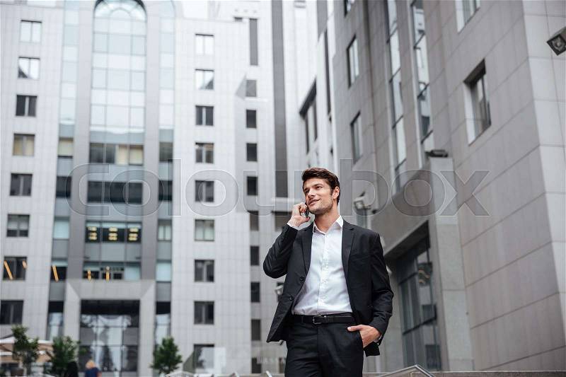 Smiling young businessman talking on mobile phone in the city, stock photo