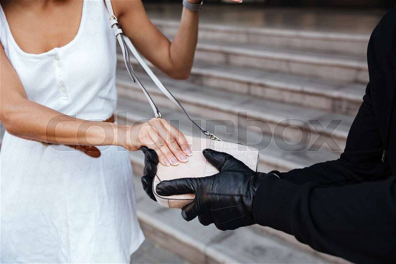 Closeup of criminal man in gloves stealing woman bag outdoors, stock photo