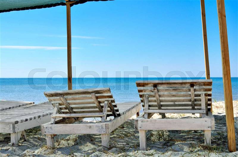 Wooden sunbeds on the background of blue sea. Resorts, vacation and seascapes, stock photo