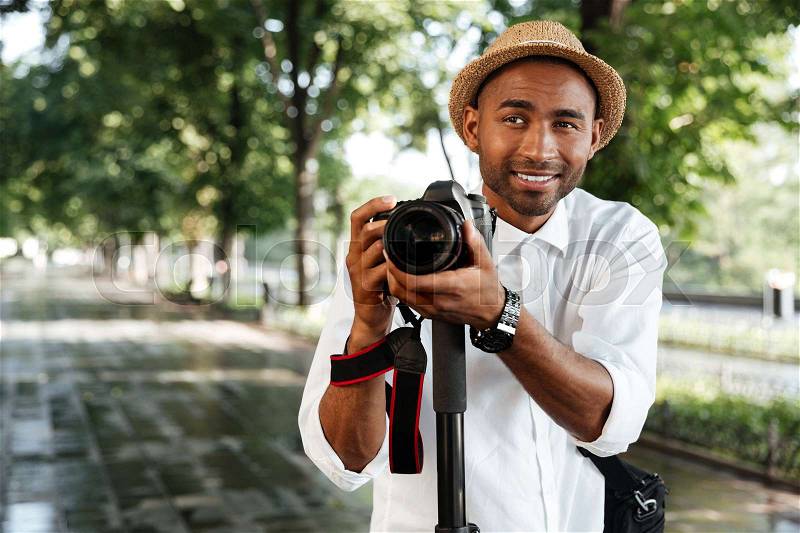 Funny black man in park with camera and hat, stock photo
