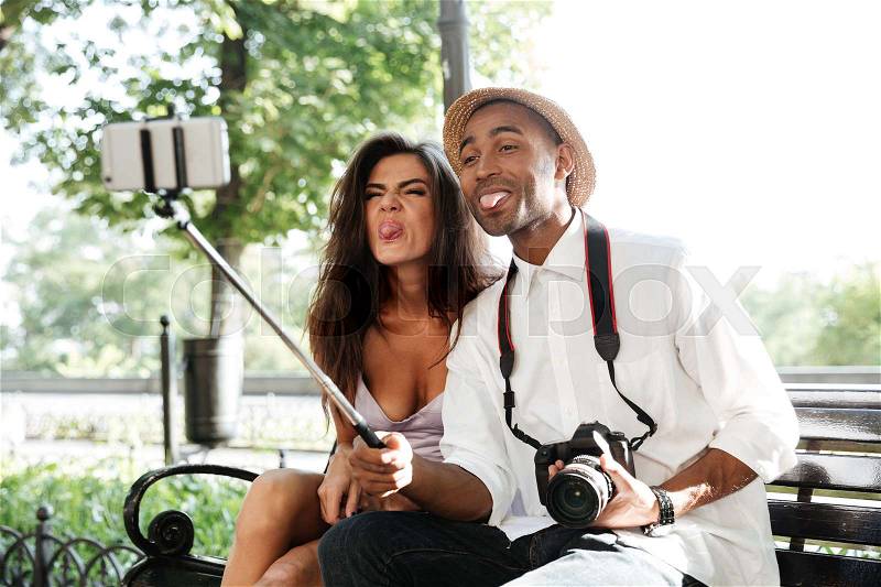 Funny hipster with model in park. makes selfie, stock photo