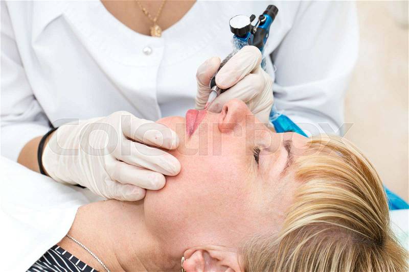 Lip tattoo woman in a beauty salon process, stock photo