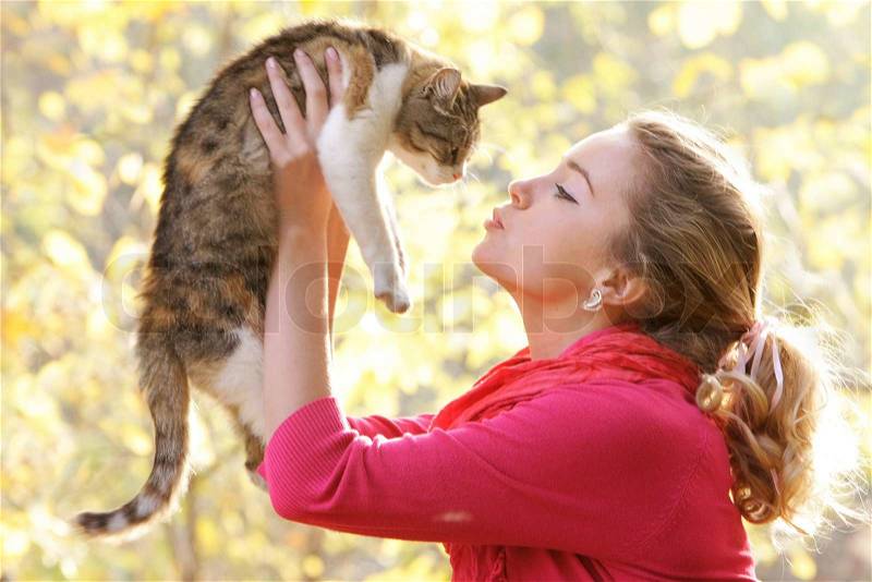 Young attractive girl with cat on natural background, stock photo