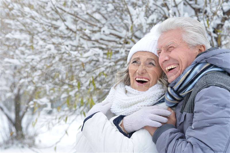 Portrait of happy senior couple hugging in winter park looking at the distance, stock photo