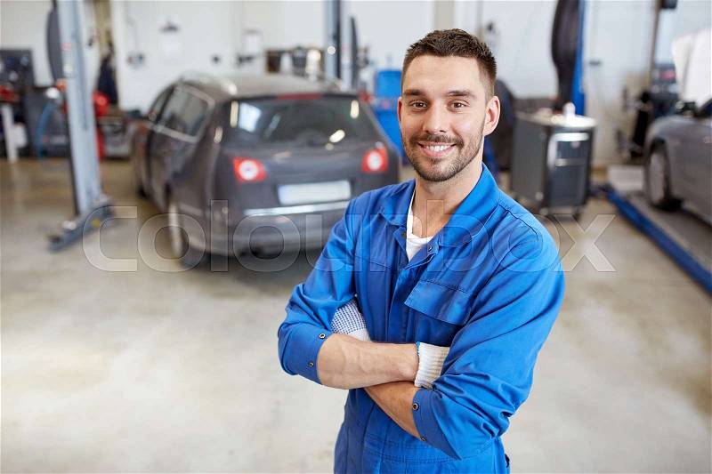 Car service, repair, maintenance and people concept - happy smiling auto mechanic man or smith at workshop, stock photo