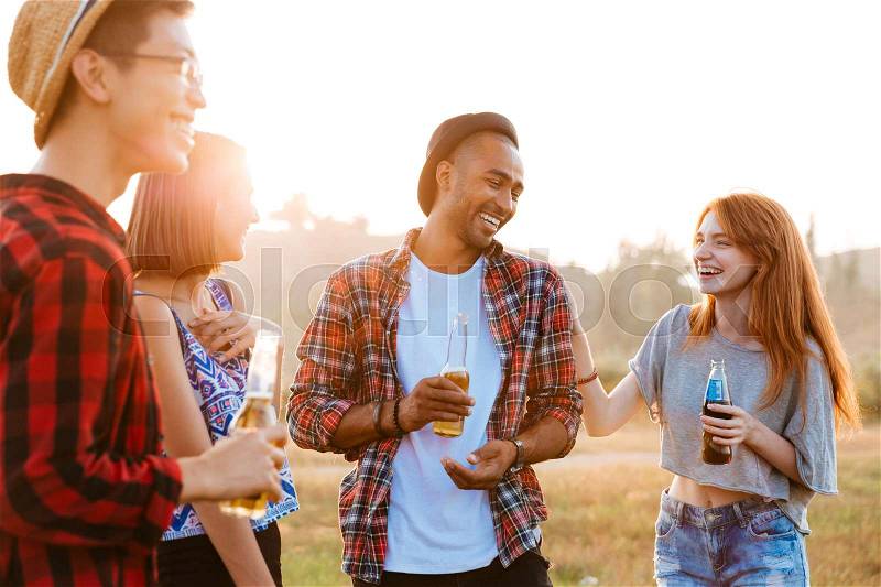 Group of happy young people laughing and drinking beer and soda outdoors, stock photo