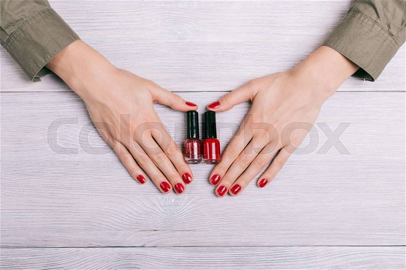 Red nail polish and female hands with manicure, top view, stock photo