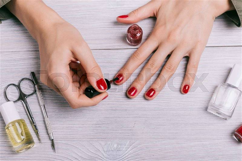 Close-up of a woman paints her nails with red lacquer, stock photo