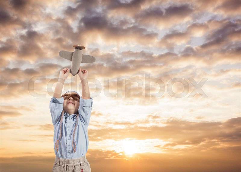 Funny toddler boy in crochet pilot hat playing with textile airplane toy, stock photo