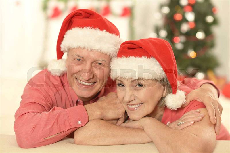 Portrait of senior couple in Santa hats smiling and looking at the camera, stock photo