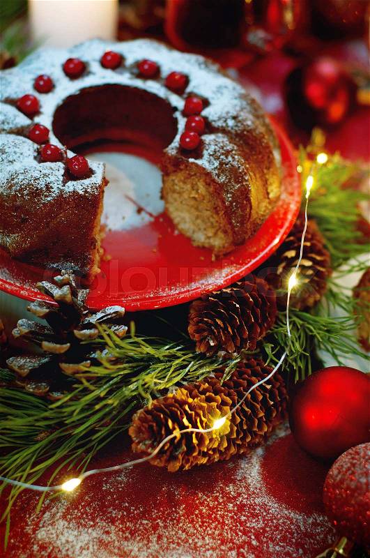 Christmas table setting. Bundt cake pudding sprinkled with sugar powder decorated with red currant and mulled wine, stock photo