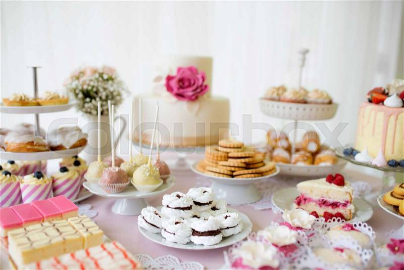 Table with loads of cakes, cupcakes, cookies and cakepops. Studio shot, stock photo