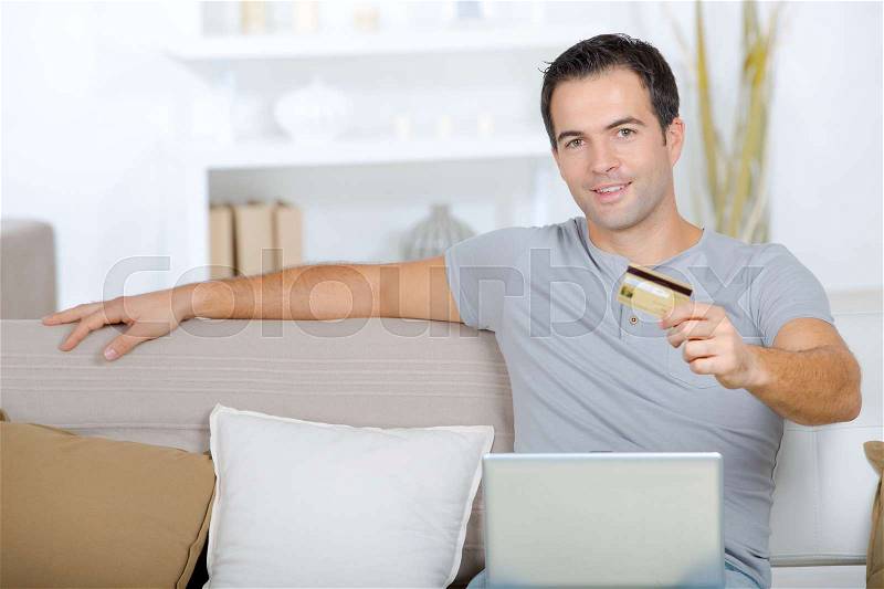 Happy man buying online in his living room, stock photo