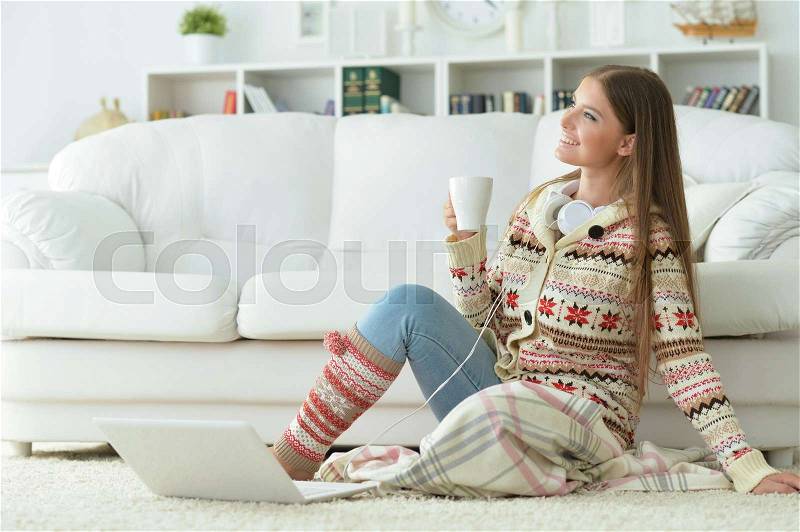 Young beautiful woman using laptop and drinking tea at home, stock photo