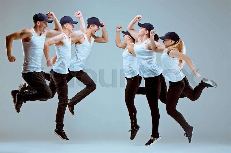 Group of men and women dancing fitness or hip hop choreography in gray studio background, stock photo