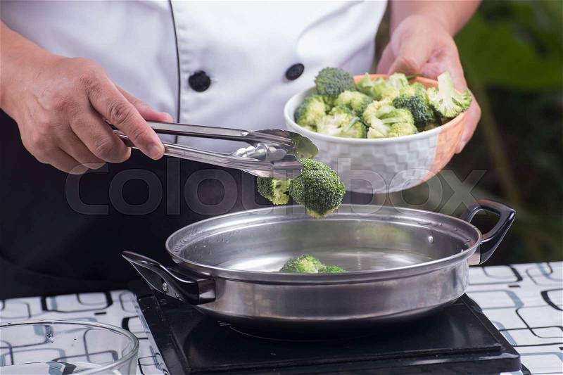 Chef putting broccoli hot water with tongs / Stir fry Broccoli concept, stock photo