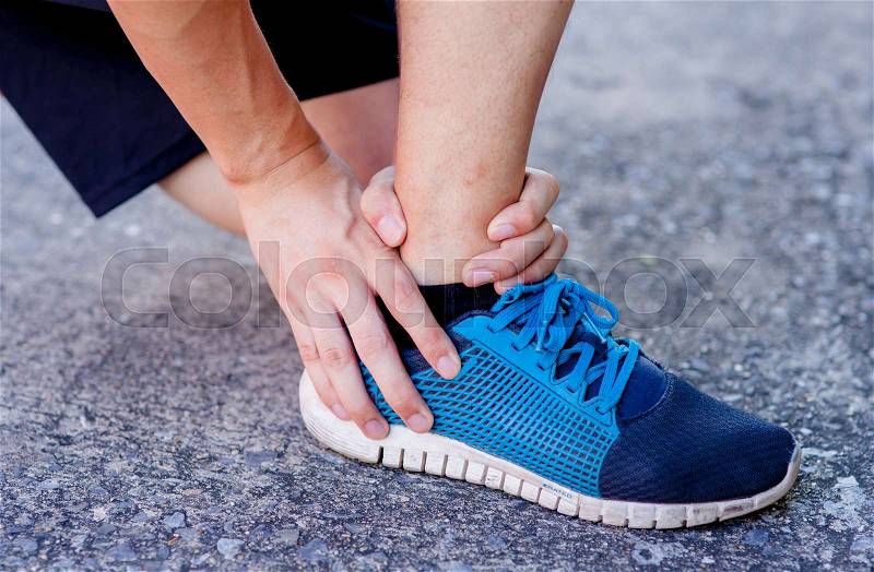 Runner touching painful twisted or broken ankle. Athlete runner training accident. Sport running ankle sprain. , stock photo