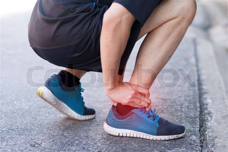 Runner touching painful twisted or broken ankle. Athlete runner training accident. Sport running ankle sprain. , stock photo