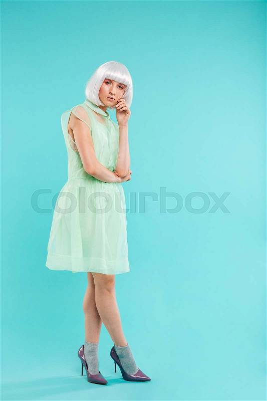 Full length of fashionable young woman in blonde wig standing and posing, stock photo
