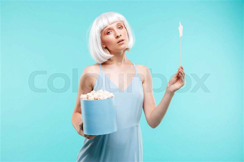 Cute blonde young woman with marshmallows holding magic stick, stock photo