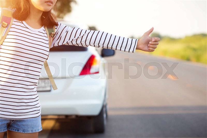 Woman hitchhiking looking for help with her broken car on the road, stock photo