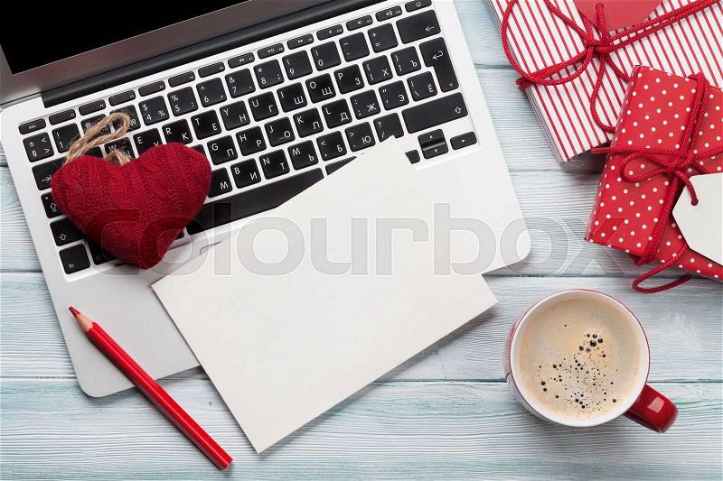 Working on laptop and wrapping christmas gifts. Top view with greeting card for your text, stock photo