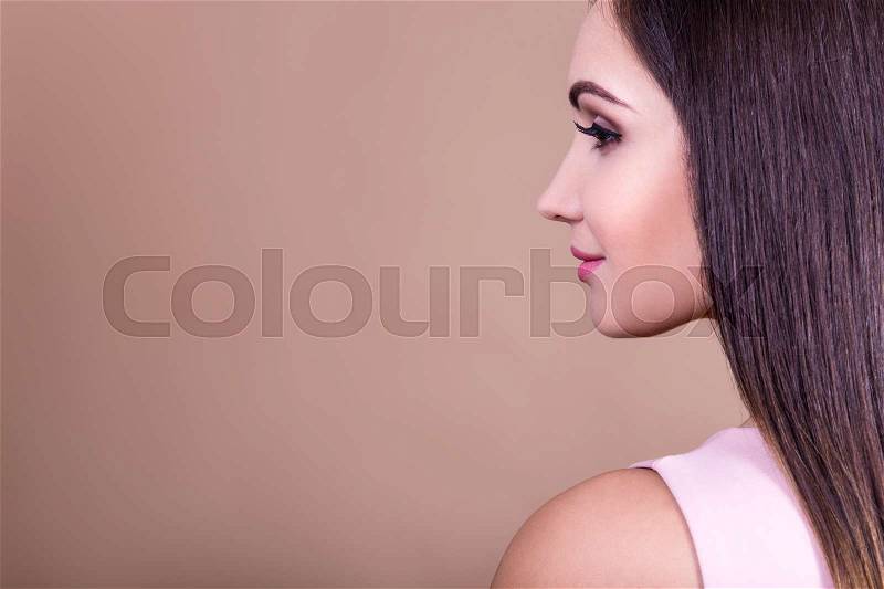Natural female beauty concept - side view of beautiful young woman and copy space over beige background, stock photo