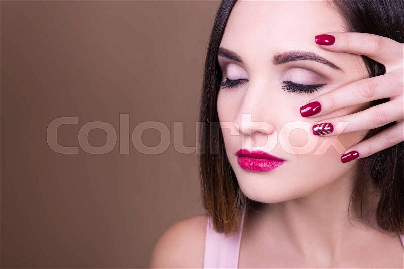 Make up and manicure concept - close up portrait of beautiful woman and copy space over beige background, stock photo