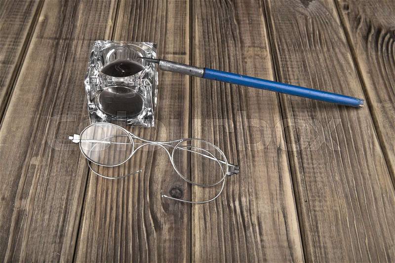 Old glasses and pen on a wooden background closeup, stock photo