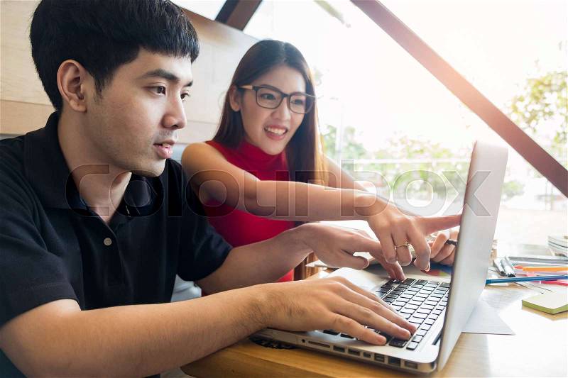Smiling friends with a hot drink using laptop in cafe at the university, stock photo