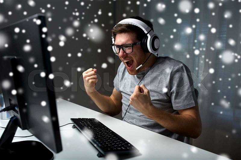 Technology, gaming, entertainment, let\'s play and people concept - man in eyeglasses with headset playing and winning computer game at home and streaming playthrough or walkthrough video over snow, stock photo
