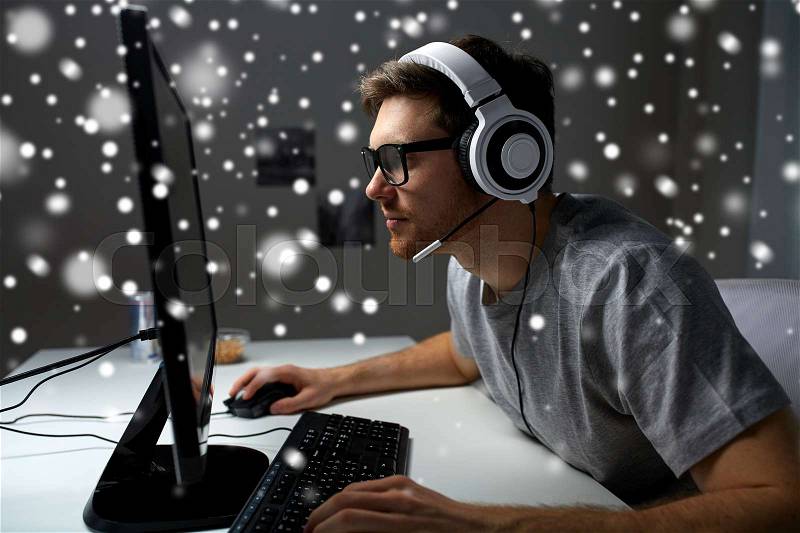 Technology, gaming, entertainment, let\'s play and people concept - young man in headset and glasses with pc computer playing game at home and streaming playthrough or walkthrough video over snow, stock photo