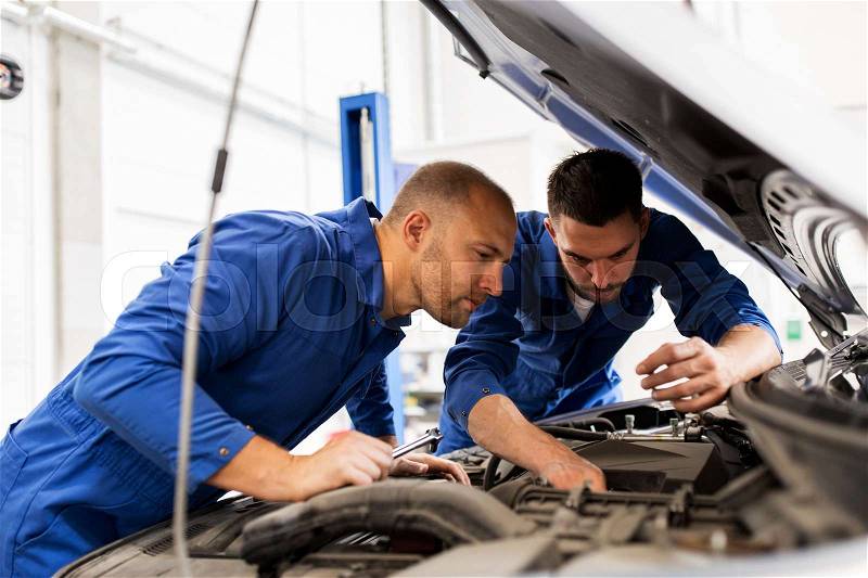 Auto service, repair, maintenance and people concept - mechanic men with wrench repairing car engine at workshop, stock photo