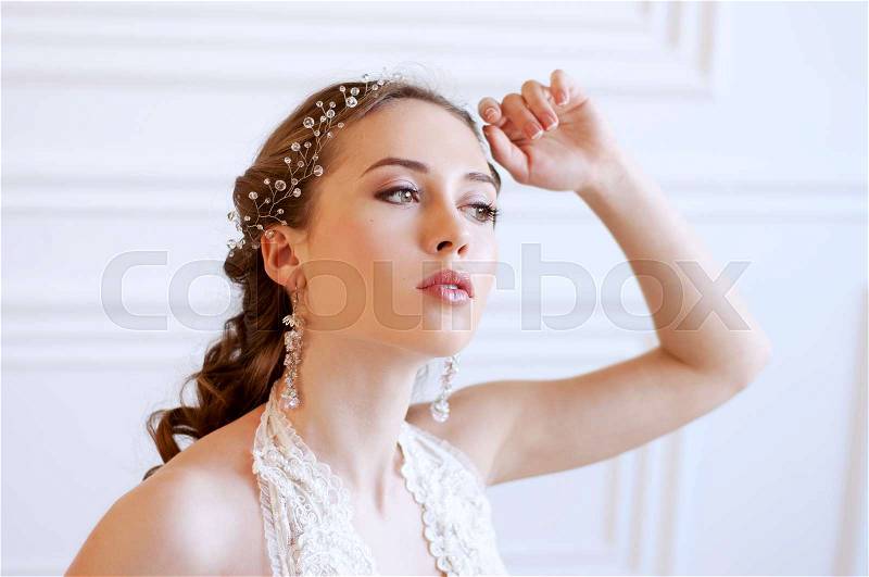 Princess style bride with long brown hair with crystal headpiece and earrings, stock photo