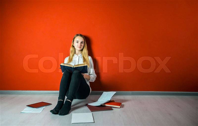 Young student girl studying sitting on the floor near books and tablet pc, stock photo