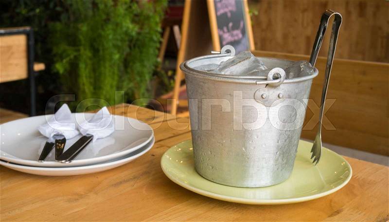 Ice bucket on wood table in restaurant, stock photo