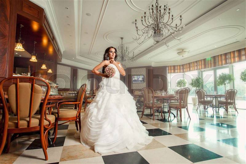 Beauty woman bride in white amazing wedding dress indoor with bouquet, stock photo