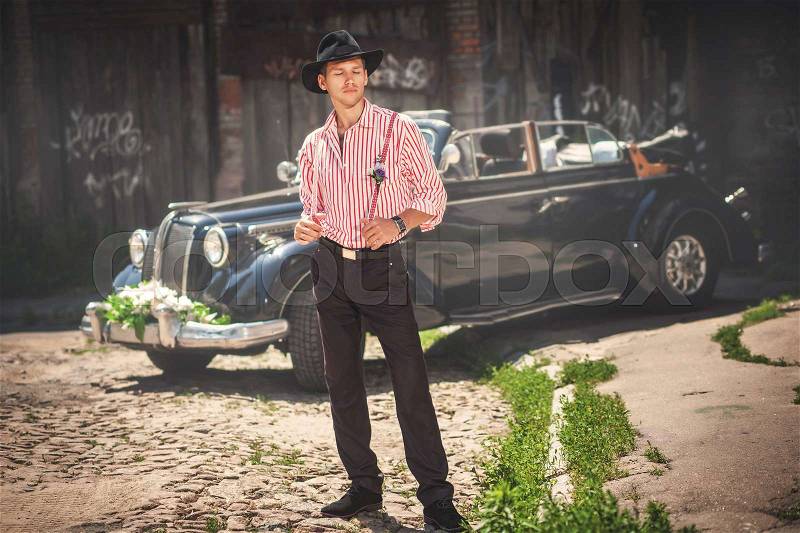 Glamour man in black hat standing near old-fashioned car, stock photo