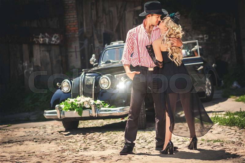 Kissing couple standing in front of old-fashioned car, stock photo