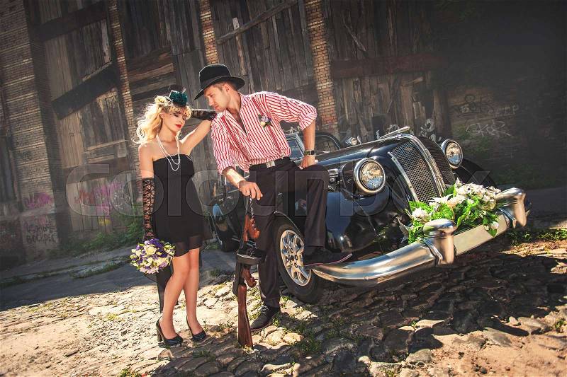 Couple in classical hats standing in front of old-fashioned car, stock photo