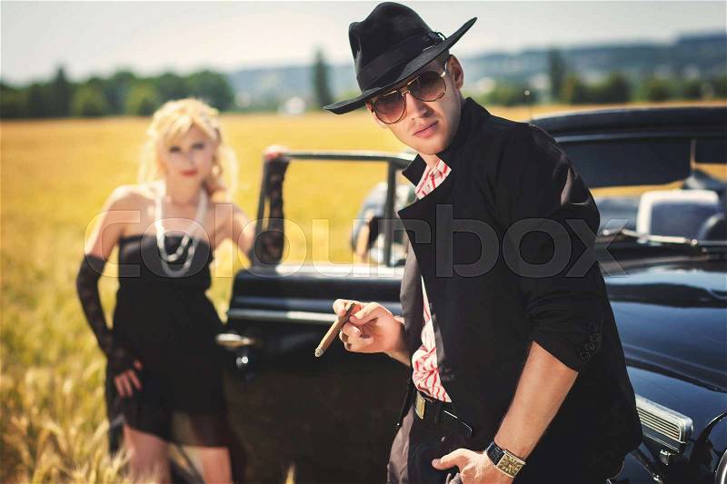 Glamour man in sunglasses and his girlfriend near car on field, stock photo