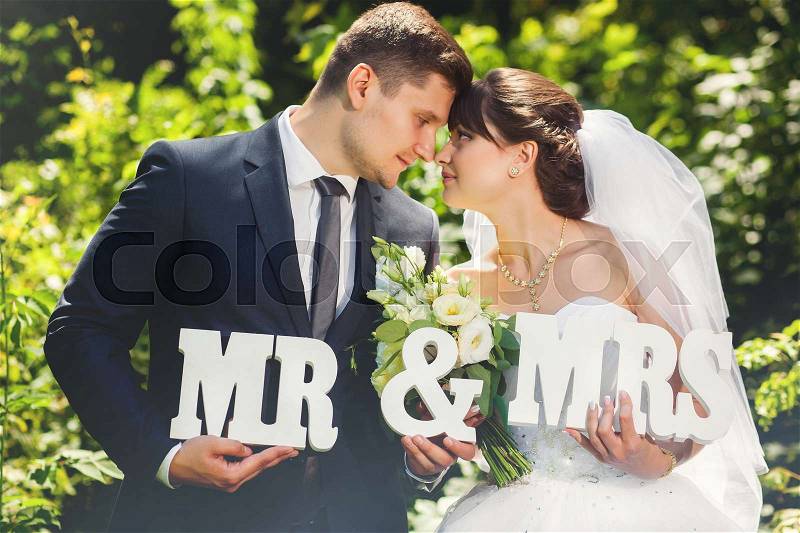 Bride and groom in summer forest with signs MR and MRS, stock photo