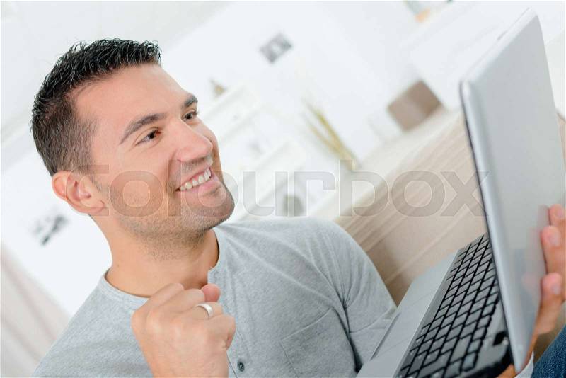 Happy man working with laptop indoors, stock photo
