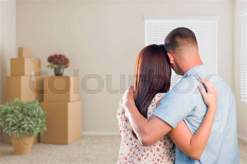 Young Military Couple Facing Empty Room with Packed Moving and Potted Plants, stock photo