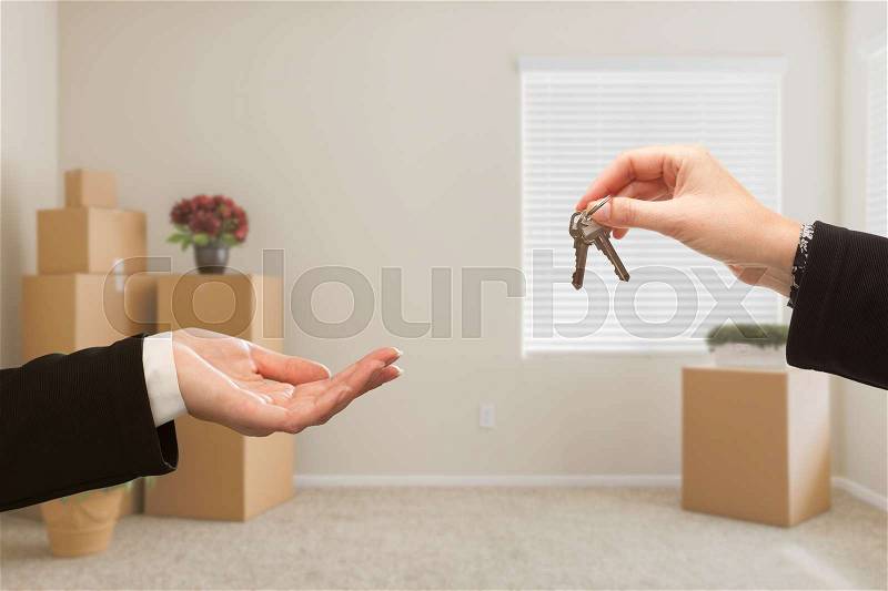 Woman Handing Over House Keys In Room with Packed Moving Boxes, stock photo