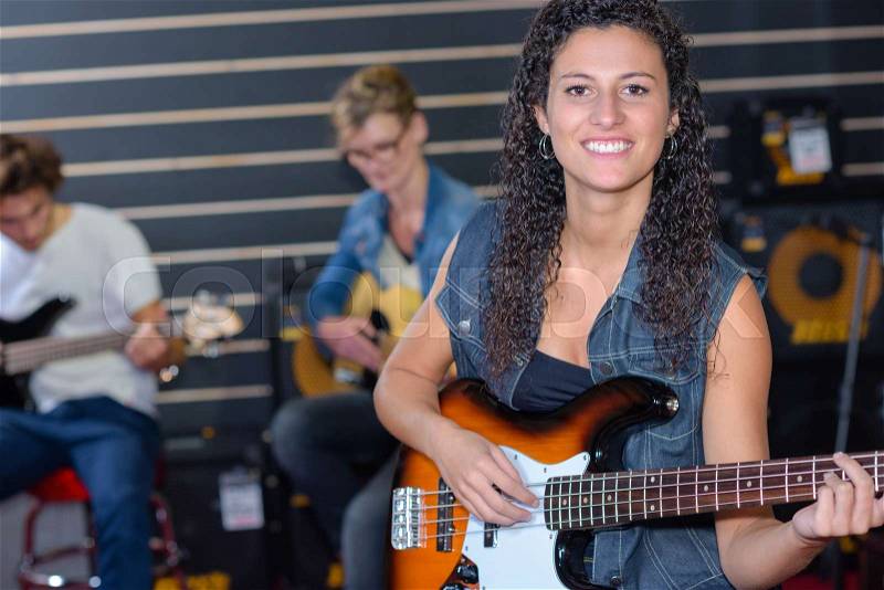 Happy girl playing an acoustic guitar in a band, stock photo